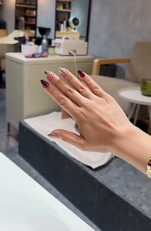 Mano con uñas vino con diseño, dentro del estudio