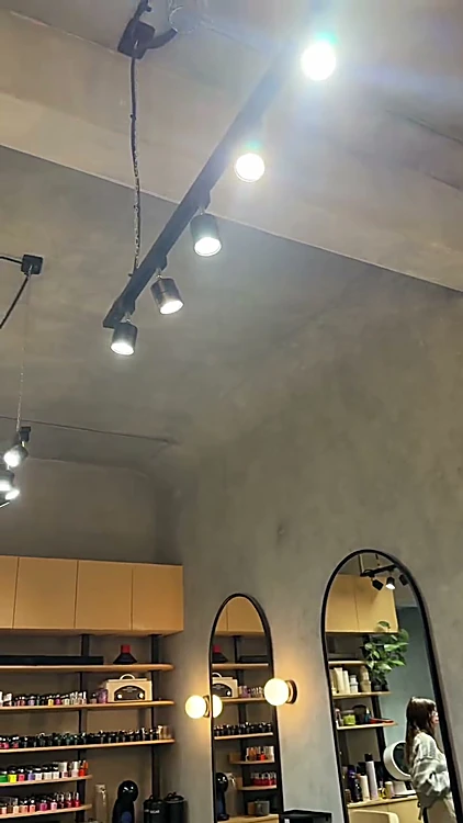 Repisas de madera llenas de esmaltes junto a espejos en arco con lámparas