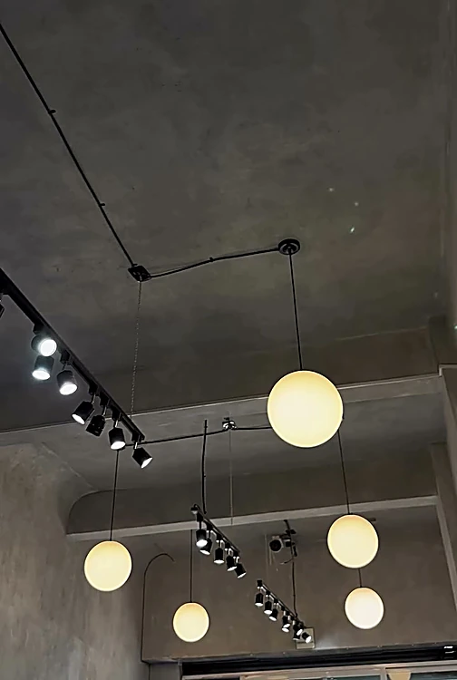 Techo de microcemento con rieles de luz y lámparas de globo encendidas
